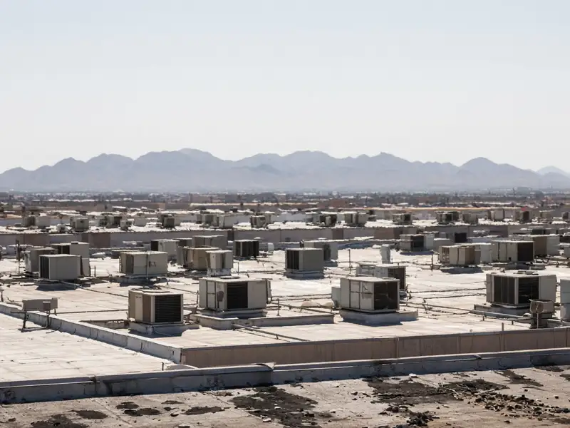 Rooftops covered in HVAC units with hazy desert mountains behind